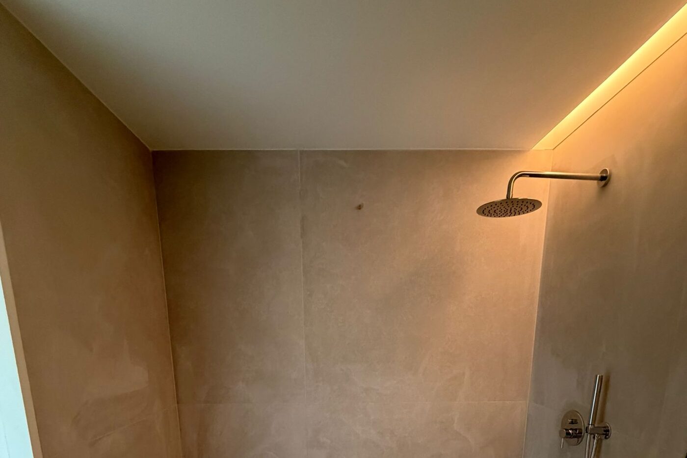 Base de duche nova instalada, com coluna de duche e iluminação embutida na parede