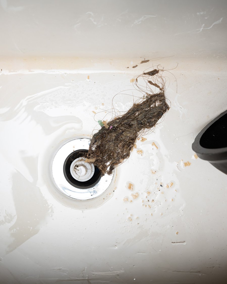 Ralo de casa de banho entupido com cabelo e resíduos