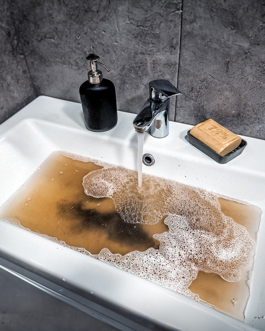 Lavatório com água suja e espuma, evidenciando mau cheiro na canalização