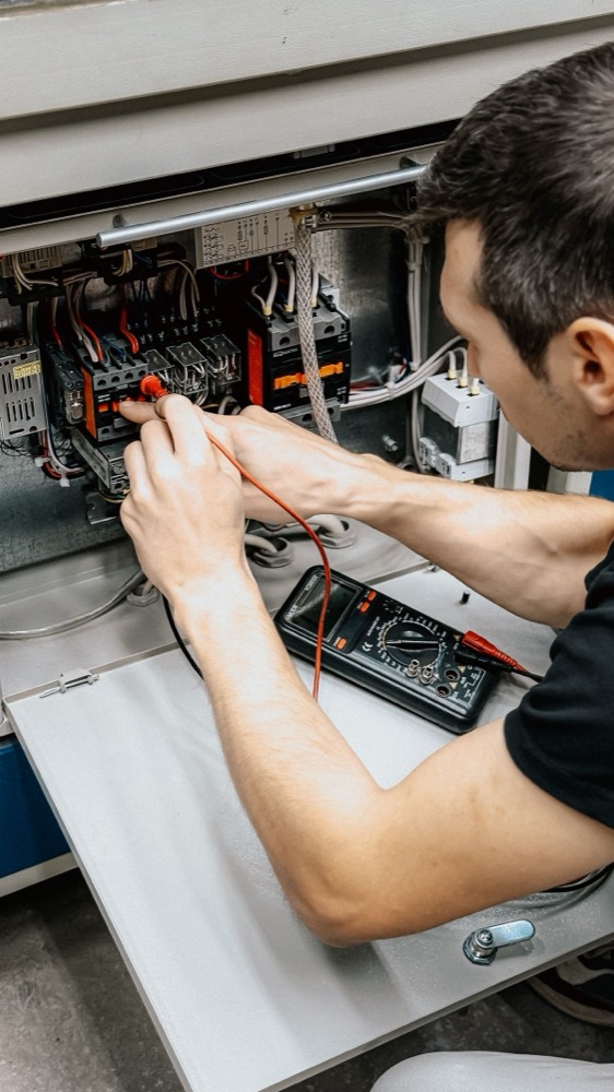 Eletricista a diagnosticar quadro elétrico com multímetro